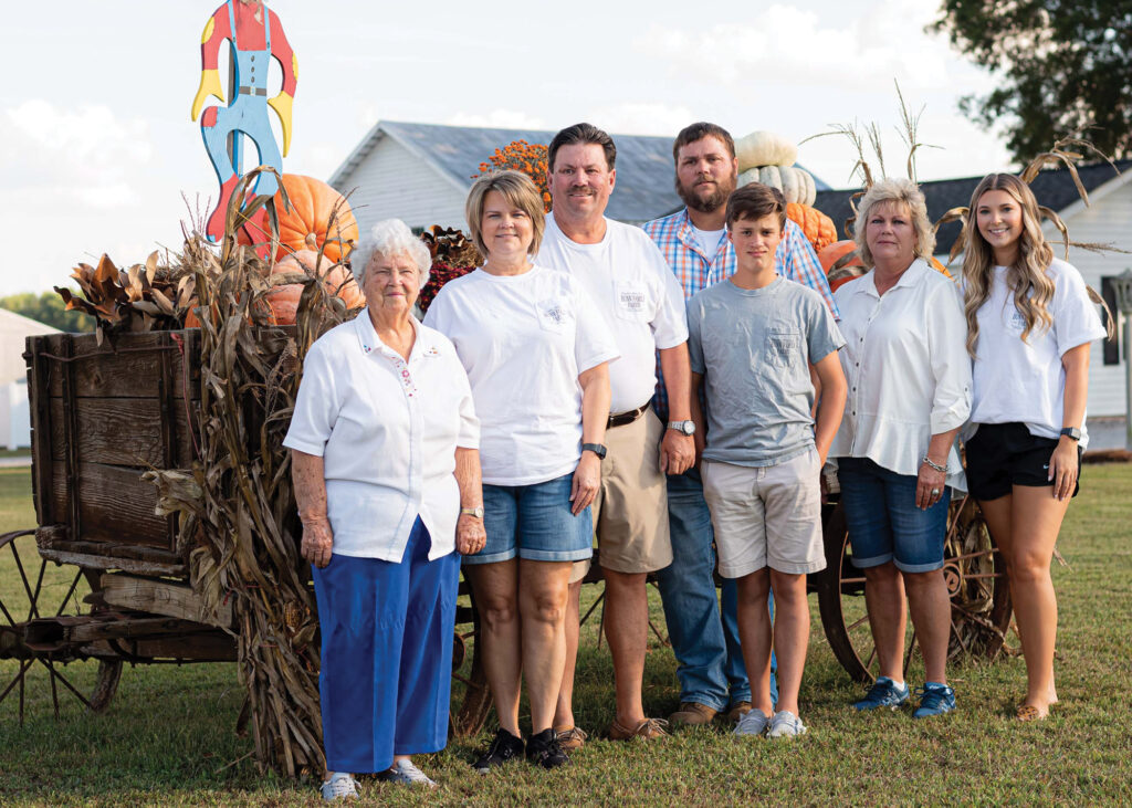 A family stands in front of a wagon with harvest.