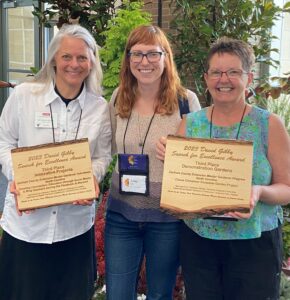 Three women display award plaques.